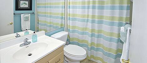 A bathroom with a striped shower curtain, a white sink, and a toilet.