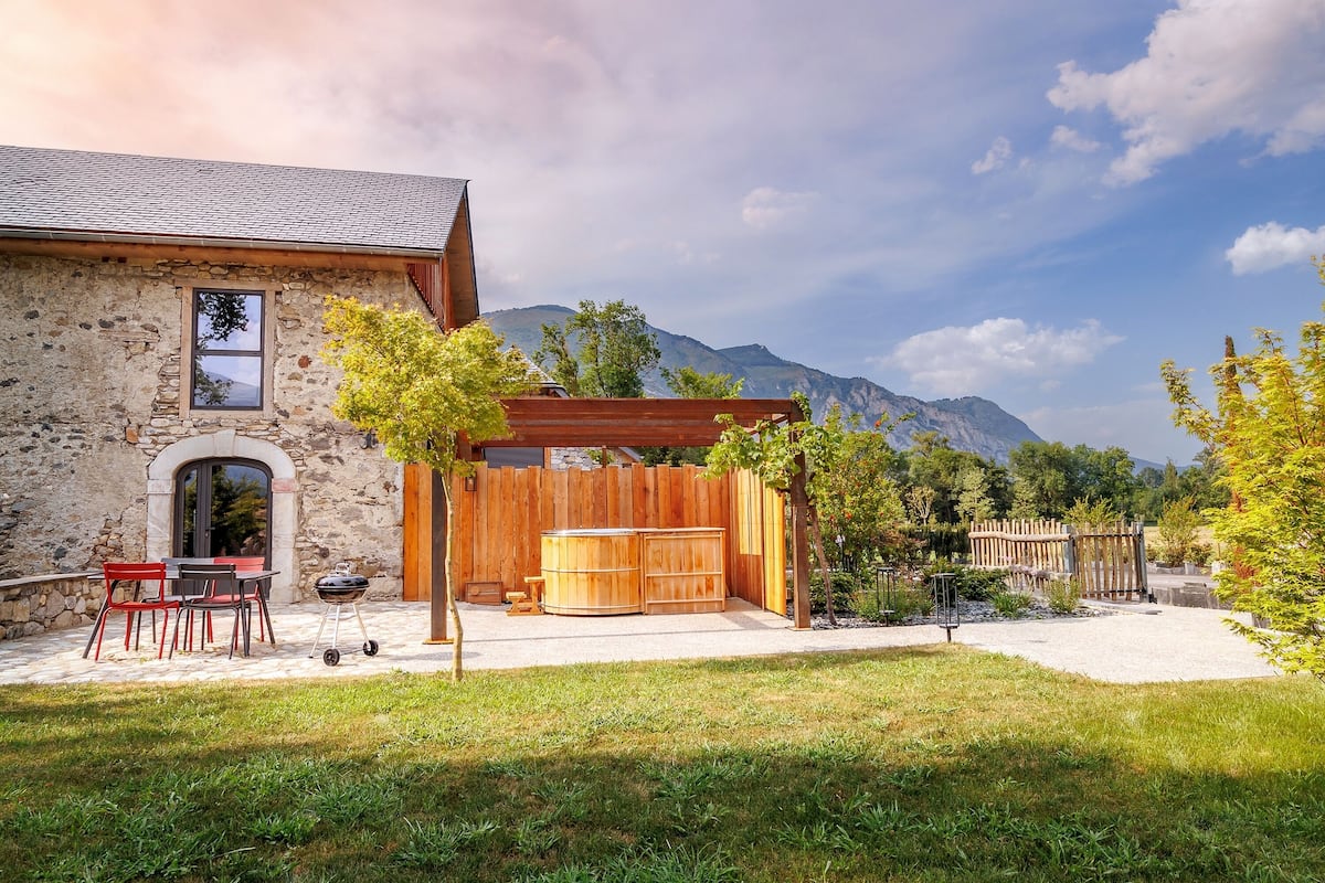 A stone building with a patio, outdoor seating, and a wooden pergola.