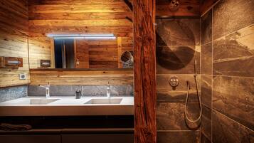 Un baño moderno con paneles de madera, lavamanos doble y ducha con cabezal de ducha manual.