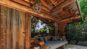 A log cabin with a built-in sofa and a large window overlooking a garden.