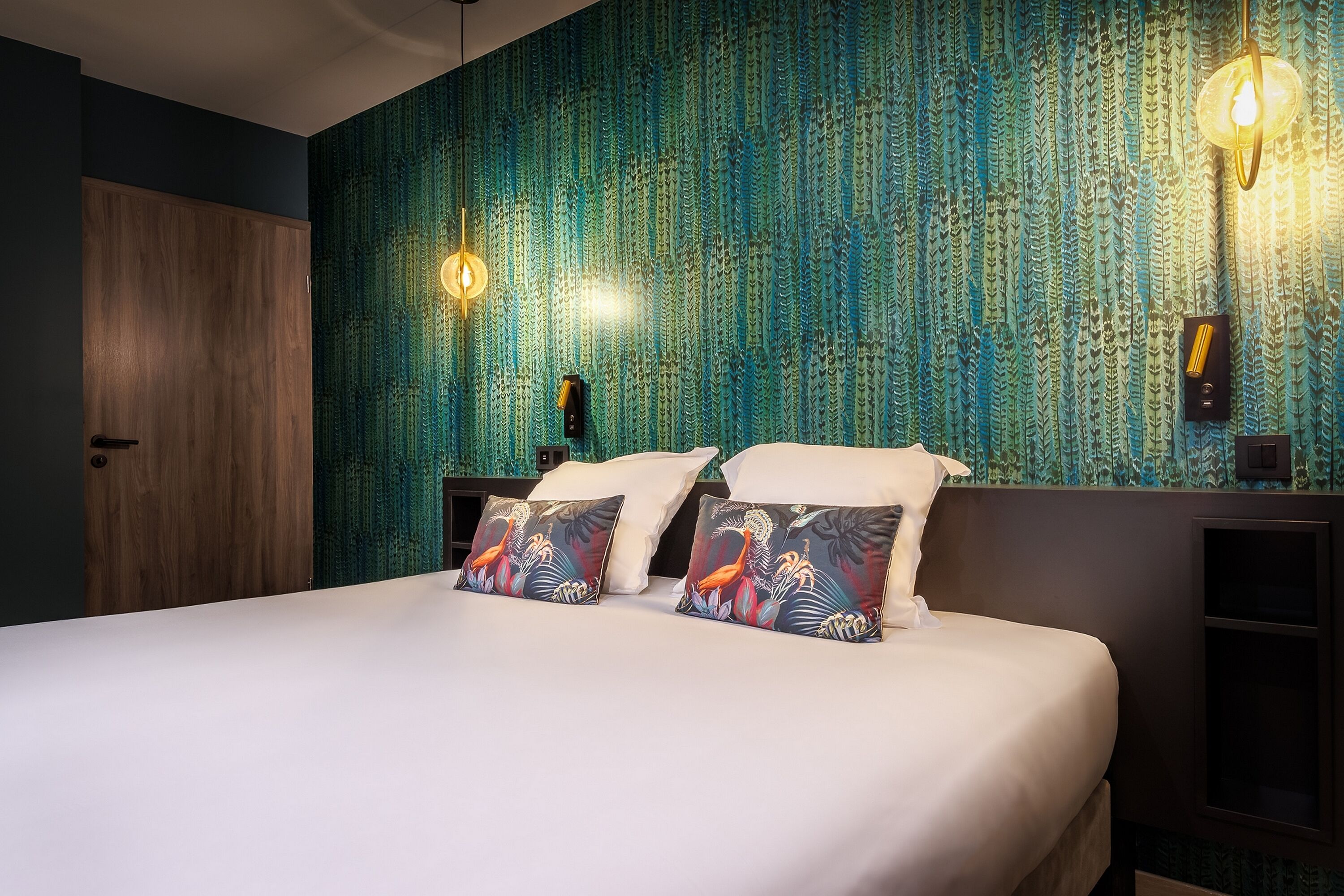 A hotel room with a bed, two wall-mounted lamps, and a patterned wallpaper.