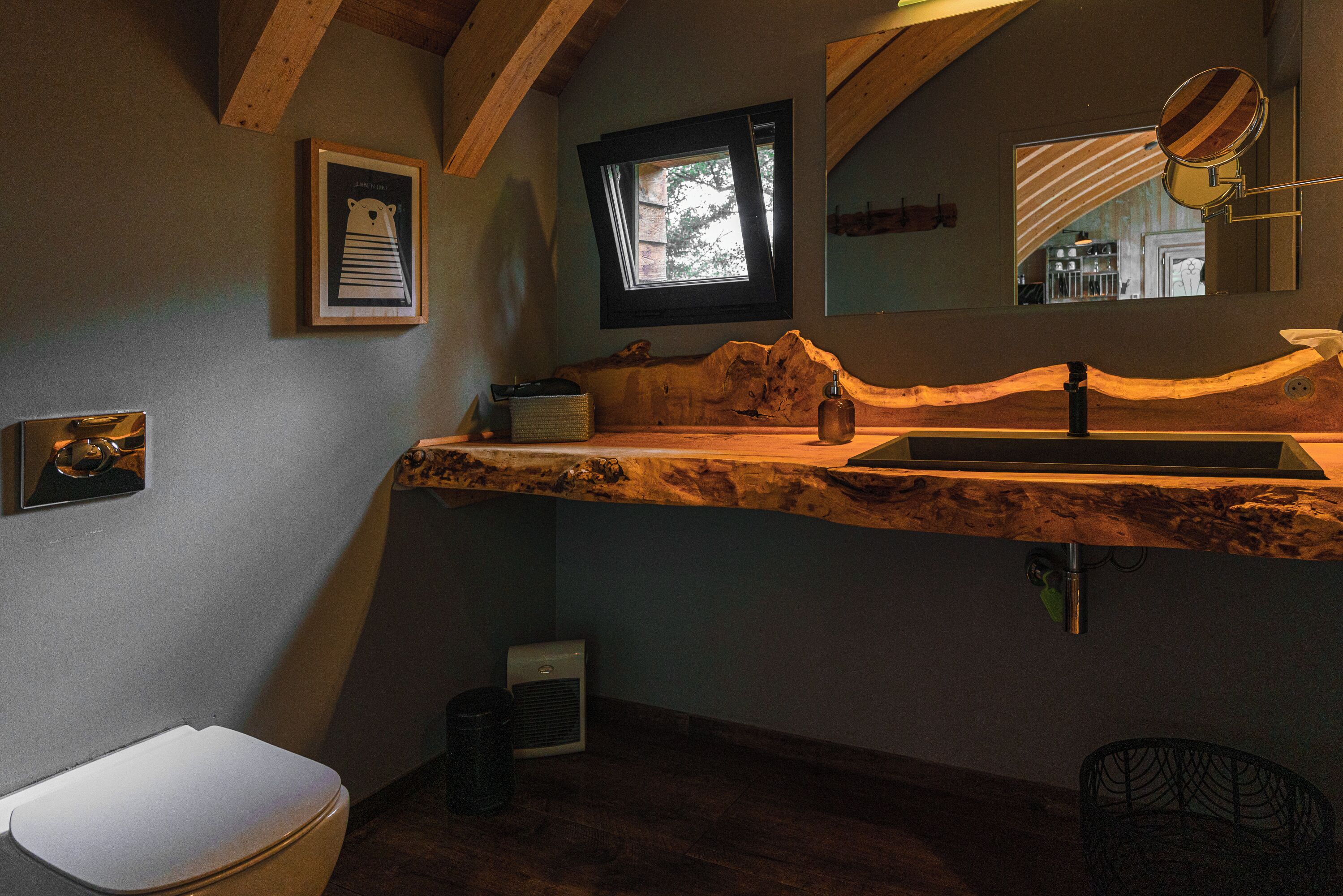 Une salle de bain avec un meuble-lavabo en bois, une fenêtre, un miroir et un tableau encadré au mur.