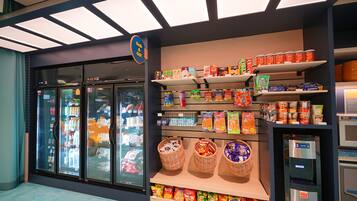 A grocery store with refrigerated sections, shelves stocked with snacks, and a self-serve beverage machine.