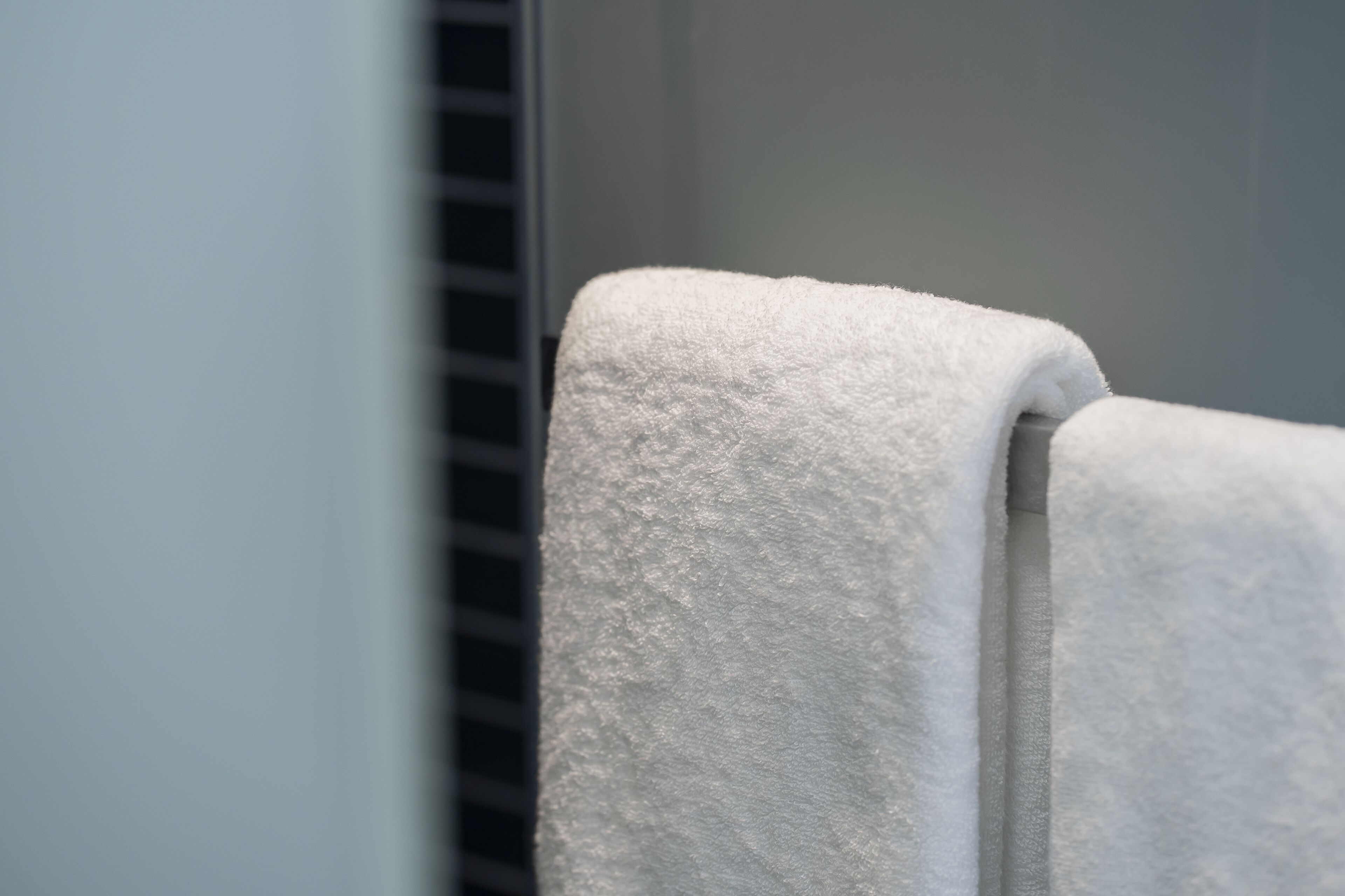 A white towel hanging on a metal towel rack.