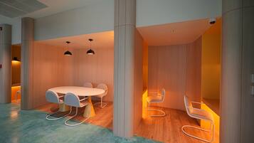 A modern conference room with a round table and white chairs, wooden panel walls, and a wooden floor.