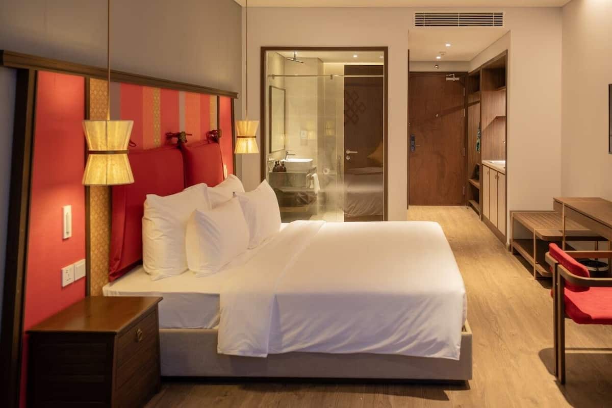 Een hotelkamer met een bed, bedlampjes, een bureau en een kledingkast.