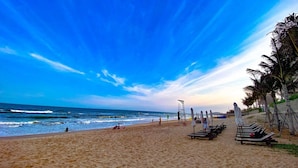 A beach with umbrellas, lounge chairs, and a lifeguard tower.