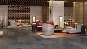 A spacious lobby with modern seating, a decorative wall with framed items, and a patterned partition.