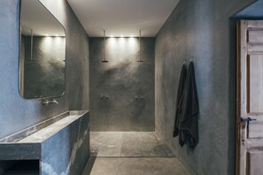 A modern bathroom with a large mirror, a marble countertop, and a shower area.