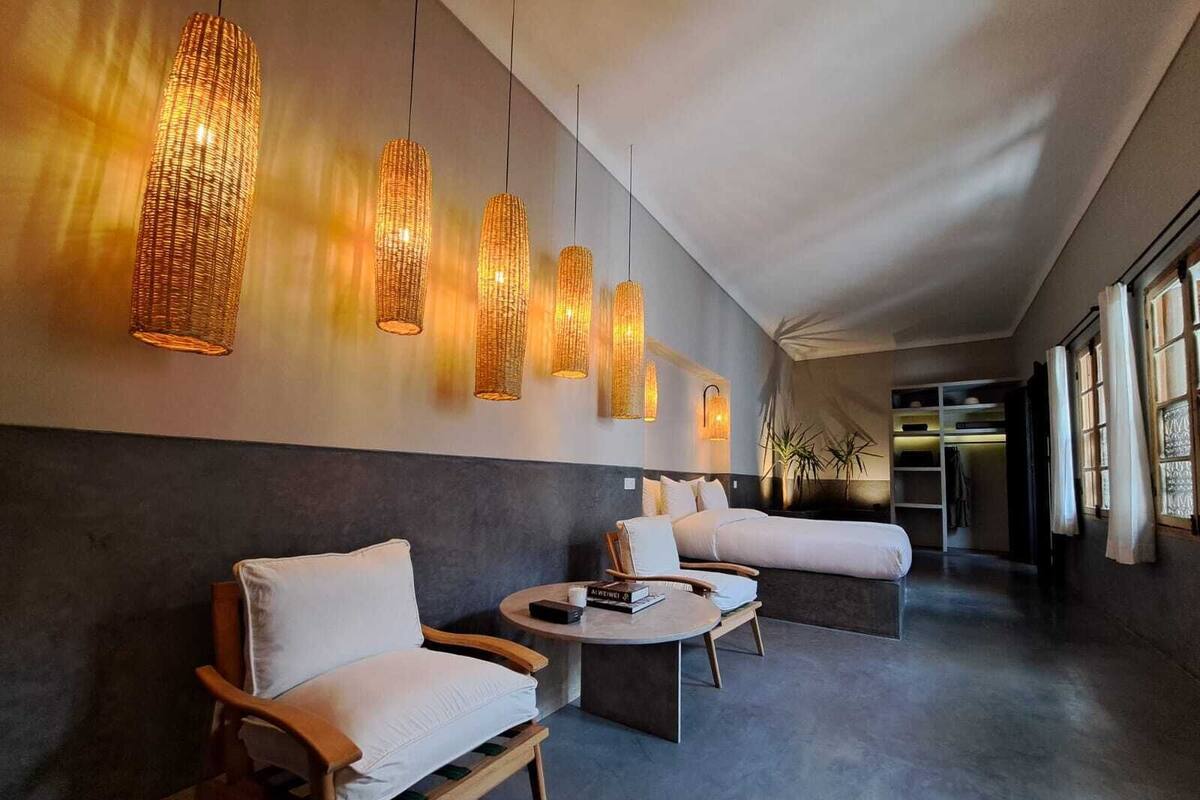 Un moderno vestíbulo de hotel con una zona de estar, una cama grande y una lámpara fijada a la pared.