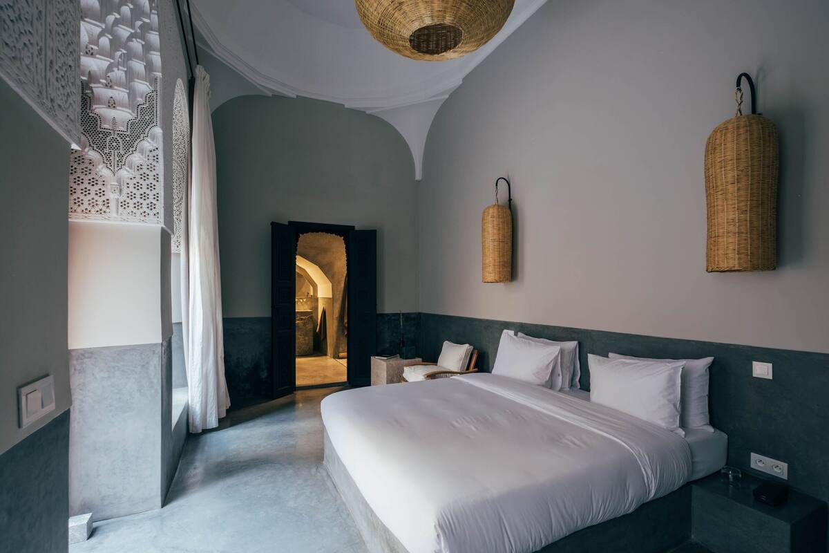 Habitación de hotel moderna con una cama grande, una mesita y una cesta colgante.