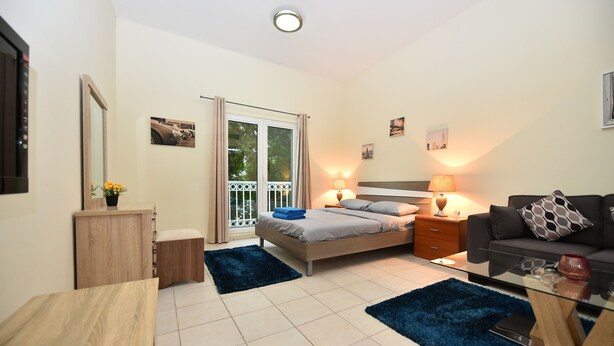 Um quarto moderno com cama, mesas de cabeceira, sofá e mesa de centro de vidro.