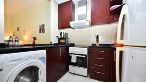 Uma cozinha compacta equipada com máquina de lavar, forno, micro-ondas e frigorífico.