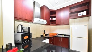 Uma cozinha com armários de madeira escura, geladeira branca e bancada preta.
