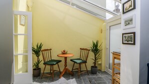 Une pièce de taille modeste, avec deux chaises en bois, une petite table ronde et un tapis tissé.