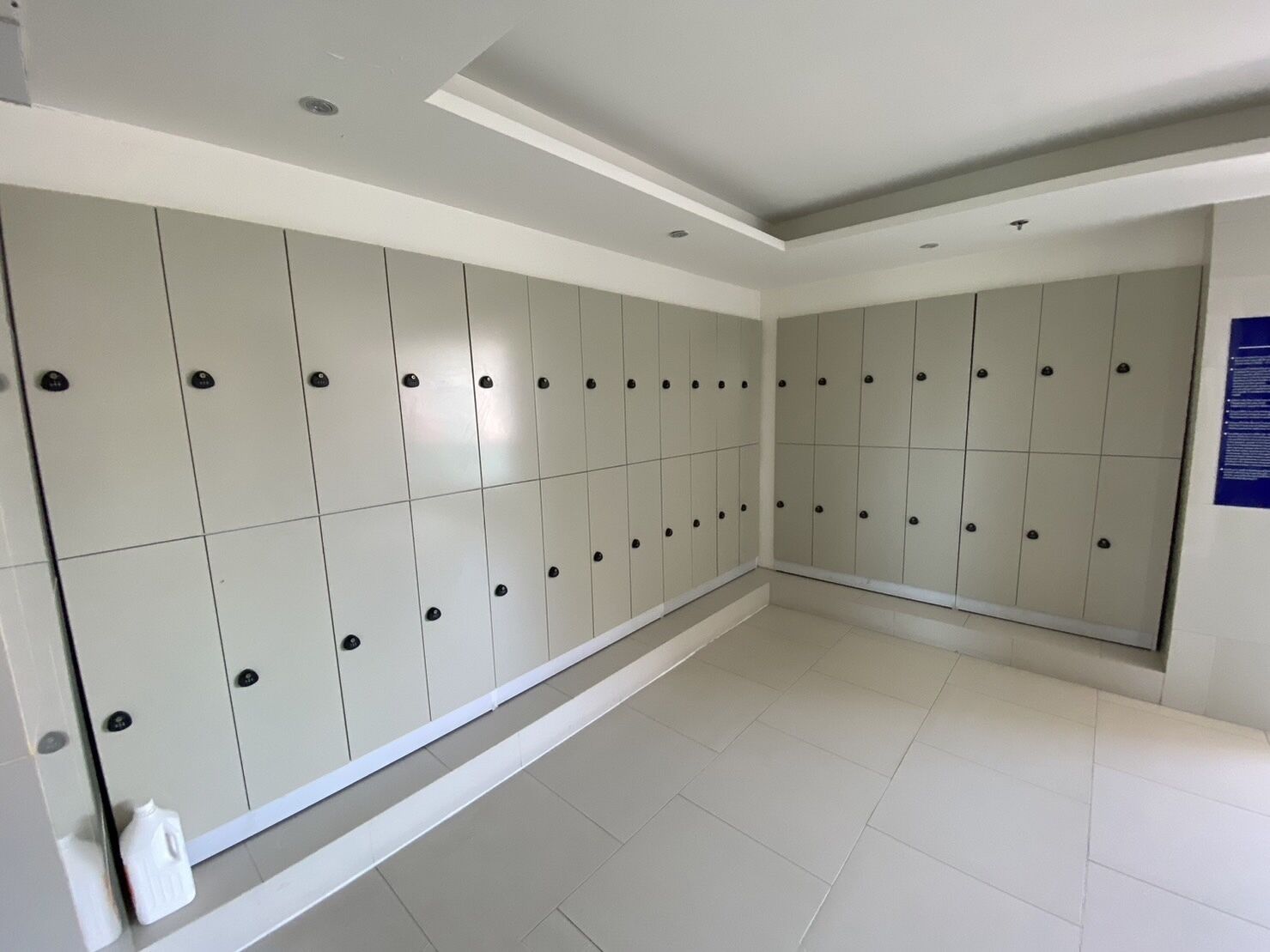 A clean, modern bathroom with white lockers and a tiled floor.