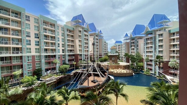 A resort with multiple buildings, a central pool, and palm trees. - Grande Caribbean by PSR (Pattaya)