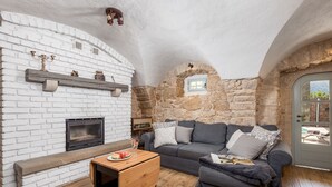 A cozy living room with a fireplace, stone walls, a grey sofa, and a wooden coffee table. - Ivka in Tribalj With 4 Bedrooms and 4 Bathrooms (Vinodol)