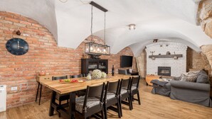 A dining area with a wooden table and chairs, a brick wall, a clock, and a fireplace. - Ivka in Tribalj With 4 Bedrooms and 4 Bathrooms (Vinodol)