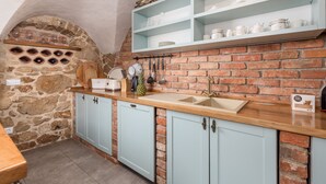 A kitchen with a stone archway, light blue cabinets, a wooden countertop, and a brick wall. - Ivka in Tribalj With 4 Bedrooms and 4 Bathrooms (Vinodol)