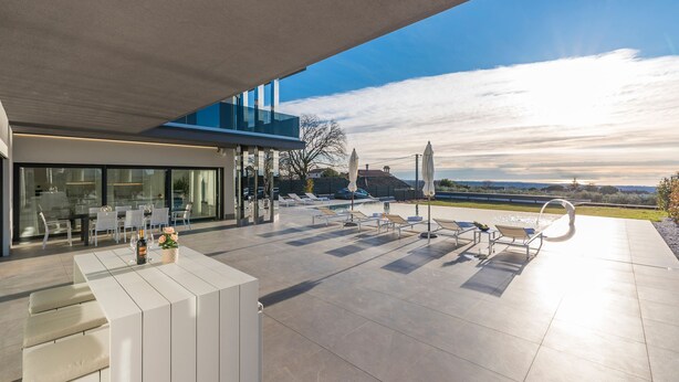 A modern outdoor patio with a pool, lounge chairs, and a dining area with tables and chairs. - Sara in Ka Telir With 5 Bedrooms and 5 Bathrooms (Kastelir-Labinci)