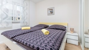 A modern bedroom with a bed, a bedside table, and a window with a view. - Antonela in Malinska (Malinska-Dubasnica)