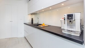 A modern kitchen with a built-in coffee machine, a sink, and a cutting board with a fruit slice. - Antonela in Malinska (Malinska-Dubasnica)
