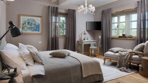 Een slaapkamer met een bed, bureau, stoel en een televisie aan de muur.