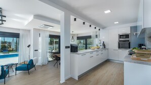 A modern kitchen with white cabinetry, a built-in oven, and a large island. - Frani in Pore With 4 Bedrooms and 4 Bathrooms (Porec)