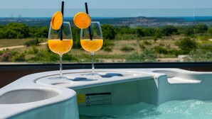 Twee glaasjes sinaasappelsap op een witte jacuzzi met uitzicht op een stadsgezicht.