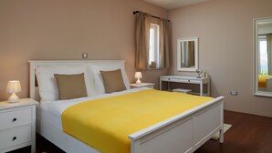 A neatly arranged bedroom with a bed, bedside tables, a dresser, and a mirror.