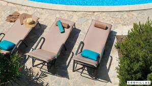A poolside area with lounge chairs, towels, and a hat.