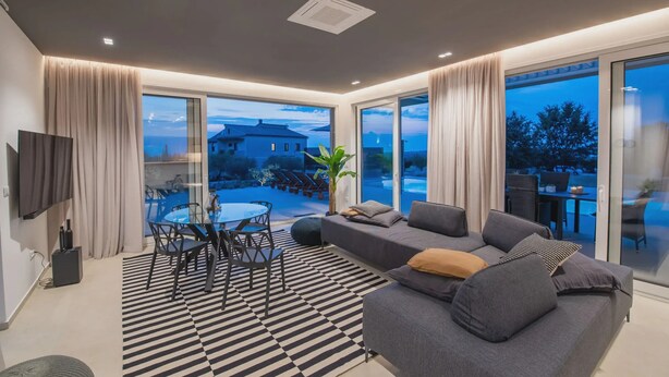 A modern living room with a sofa, a dining table with chairs, and a large window with curtains. - Vivas in Strani i kod Nove Vasi (Porec)