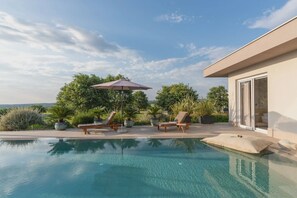 A swimming pool with lounge chairs and an umbrella, surrounded by greenery and a modern building. - Vivas in Strani i kod Nove Vasi (Porec)