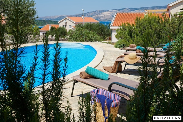 A pool area with lounge chairs and a wicker basket. - Isabella Hvar in Rudina Hvar (Stari Grad)