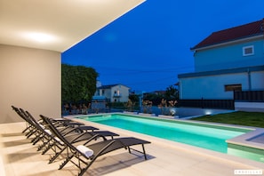 A swimming pool with lounge chairs, a clear sky, and a building in the background. - Kastel Two in Ka tel Kambelovac (Kastela)