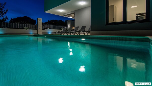 A swimming pool with lounge chairs, a modern building with large windows, and a visible kitchen area. - Kastel Two in Ka tel Kambelovac (Kastela)