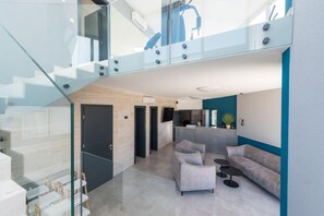 A modern interior with a staircase, a living area with a sofa and chairs, and a kitchen area. - M2 in Vir With 2 Bedrooms and 2 Bathrooms (Vir)