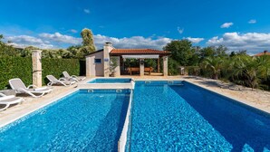 A swimming pool with lounge chairs, a covered seating area, and a stone building in the background. - Kastelir in Ka Telir (Kastelir-Labinci)