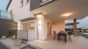 Un apartamento moderno con balcón, mobiliario exterior y zona de piscina.