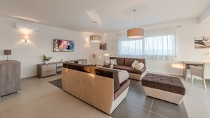 Una sala moderna con sofá, reposapiés y un comedor con mesa y sillas.