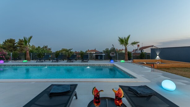 Una piscina con lettini e un tavolo con bevande.