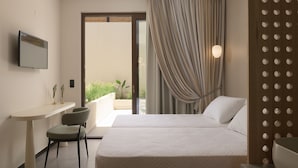 Ein Hotelzimmer mit Bett, Schreibtisch mit Stuhl, Fernseher und Blick auf Grünfläche.