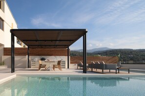 A rooftop pool area with a covered seating area, a grill, and a view of the mountains. - Villa En Paraiso, a Majestic SeaView Retreat  (Maroulas)