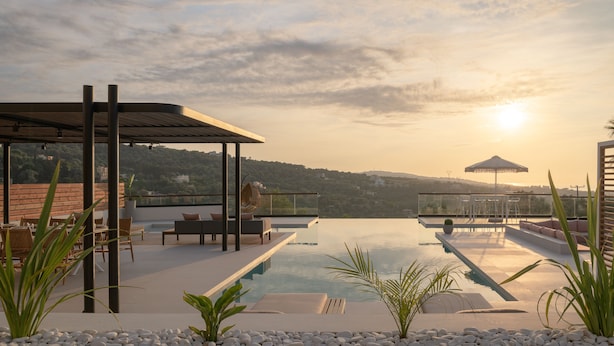 Ein Infinity-Pool auf dem Dach mit einer Pergola und Sitzbereich, mit Blick auf eine hügelige Landschaft.