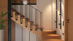 Eine moderne Treppe mit Holzstufen und schwarzen Geländern, die zu einer Zwischenebene mit einem Topfpflanzen führt.