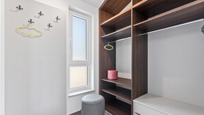 A walk-in closet with wooden shelves and a grey ottoman. - Casa Mara in Tokovci (Svetvincenat)