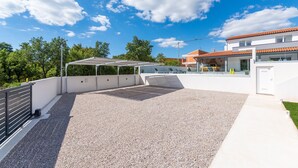 A rooftop patio with a gravel floor, a covered seating area, and a modern building in the background. - Casa Mara in Tokovci (Svetvincenat)