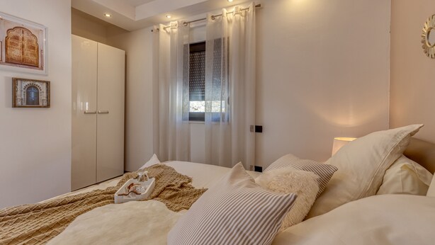 Une chambre à coucher avec un lit, des rideaux, une armoire et des éléments de décoration fixés au mur.