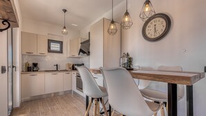 Une cuisine moderne avec des meubles blancs, une table à manger en bois et deux tabourets de bar.